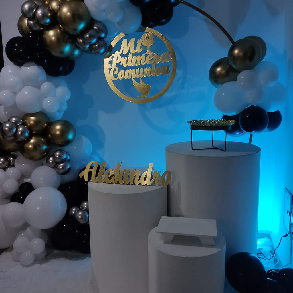 Decoración de primera comunión para hombre con globos dorados y marcos dorados con mesas blancas con un arco decorado