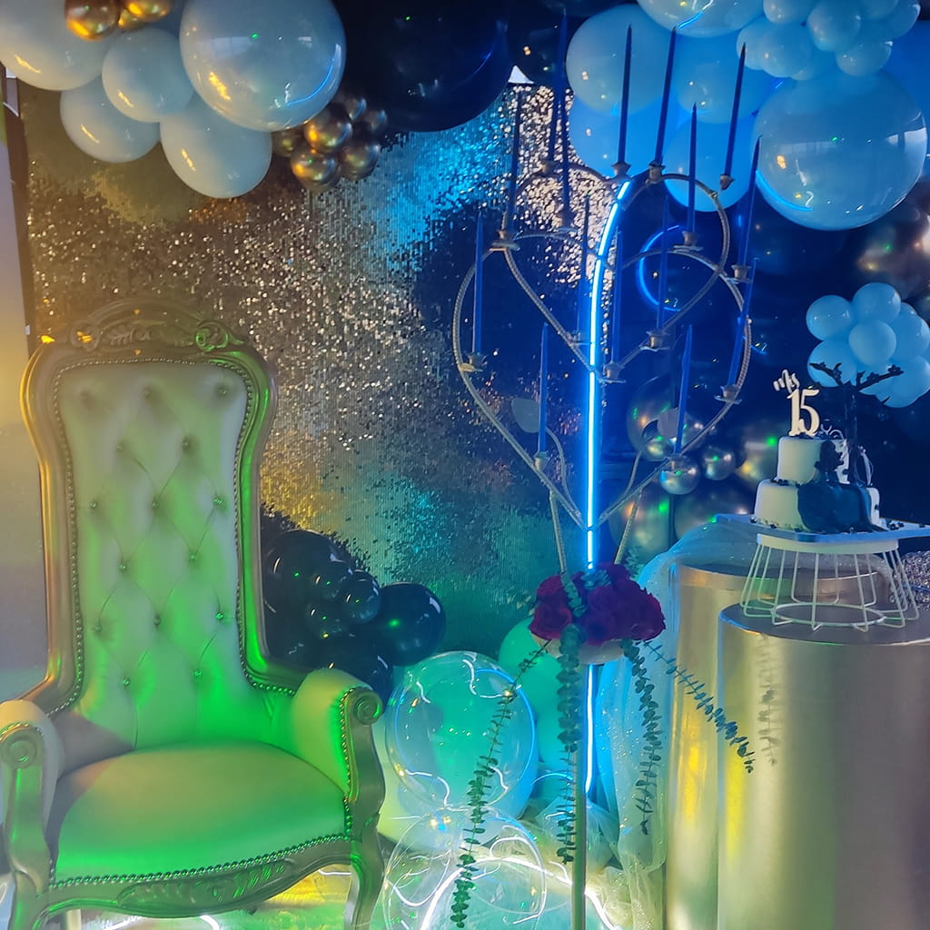 decoracion espectacular de 15 años con muchos brillos y colores y una espectacular silla