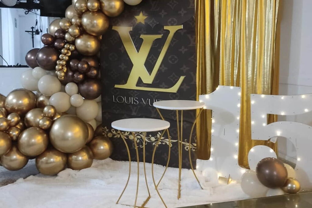 Decoración fiesta de 15 años con la temática louis vuitton con bombas doradas, cafés y el logo de la gran marca
